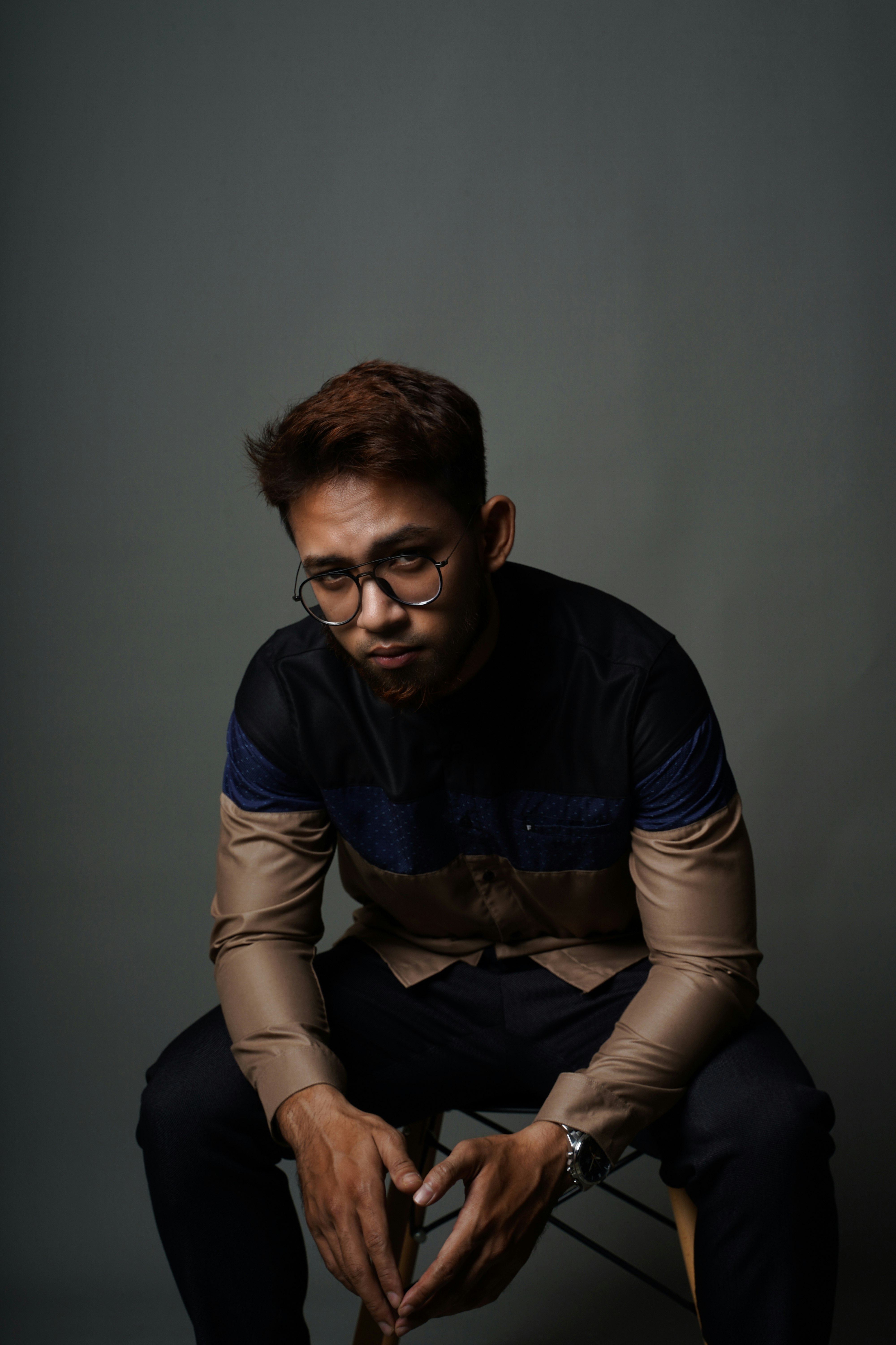 man in blue and brown long sleeve shirt sitting on chair